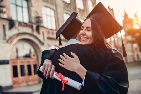 83757000-graduates-in-mantles-with-diplomas-in-hands-are-standing-near-university-and-hugging-each-other- (1).jpg